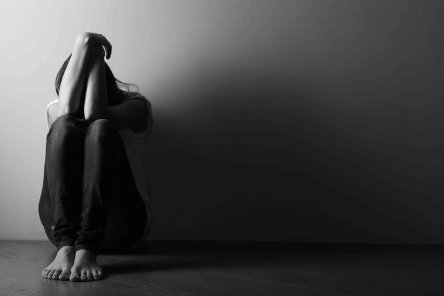 teen-girl-sitting-alone-on-the-floor-in-semi-dark-room-blk-white-image-scaled